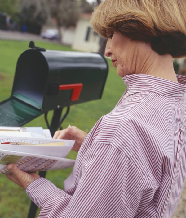 Woman checking letters from mailbox in garden