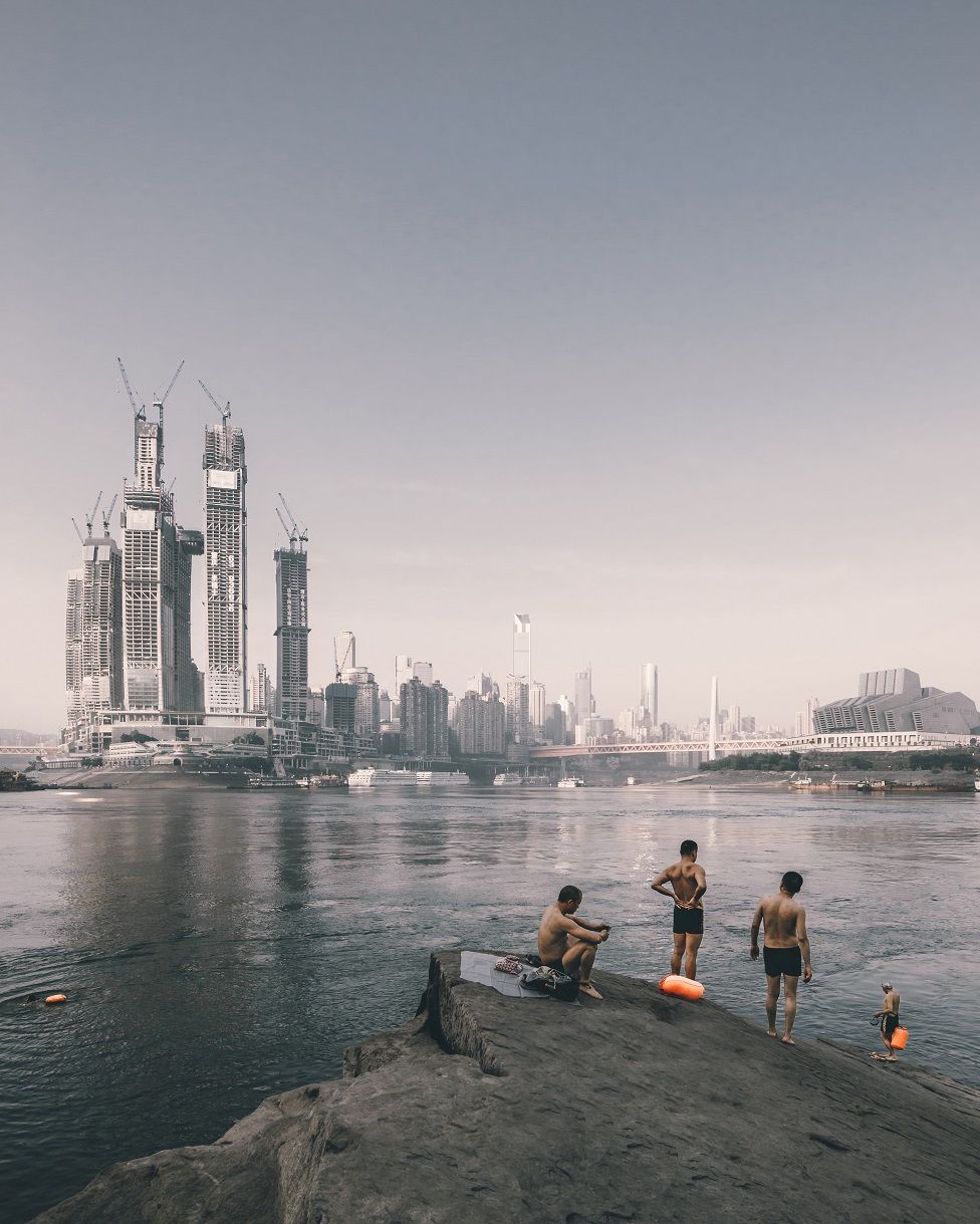 Concurso foto arquitectura. Nadadores en la orilla del río frente a la construcción de Raffles City, en Chongqing (China)