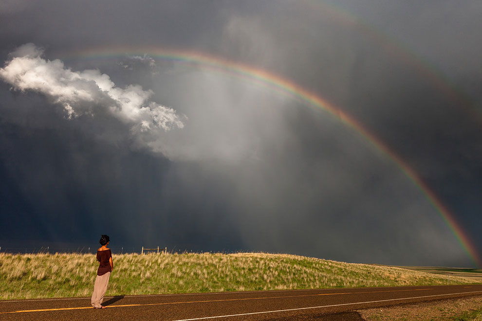 mujer junto a arcoiris y nubes