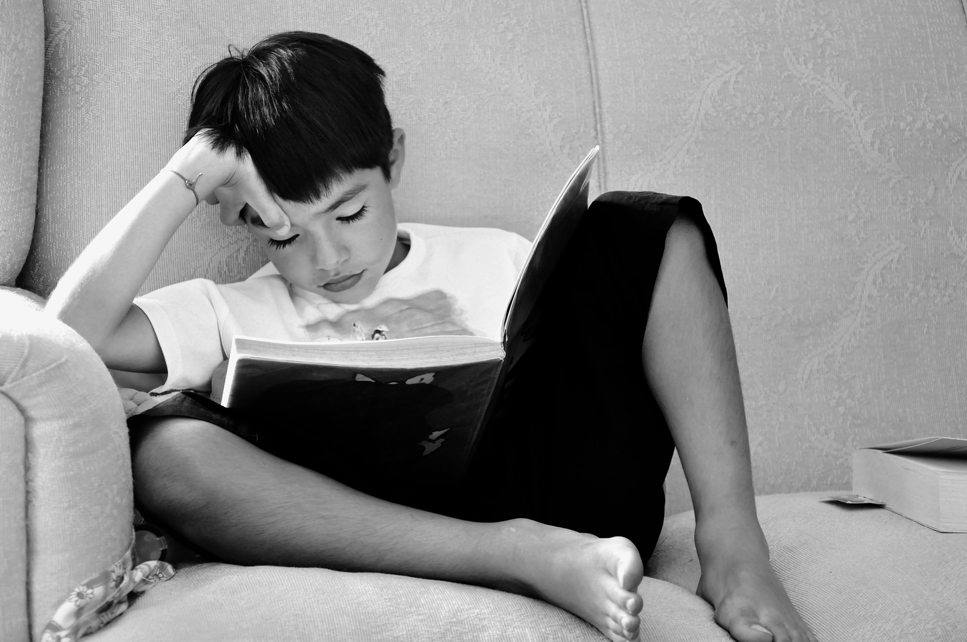 niño en sofa leyendo un libro
